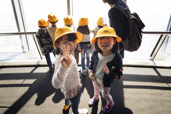 toyko, japan, research, travel, visit, spring, tokyo skytree, tallest building, city, buildings, observation deck, school children, kids, yellow hats, views, creeper, camera, click, photography, photo, decisive moment, lined, asia, peace fingers, smiles, kids, arigatou goziamsu